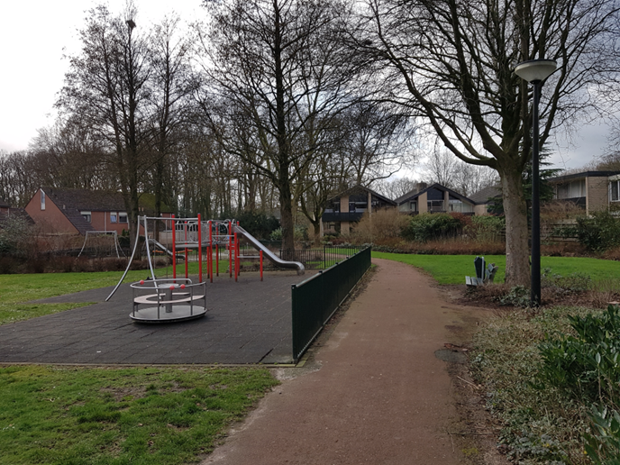 Park met speeltoestellen en huizen in de verte. Zie bijschrift onder afbeelding